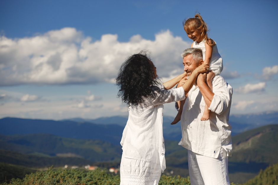 A loving older couple shares a joyful moment with their granddaughter on his shoulders, right in front of the kids.