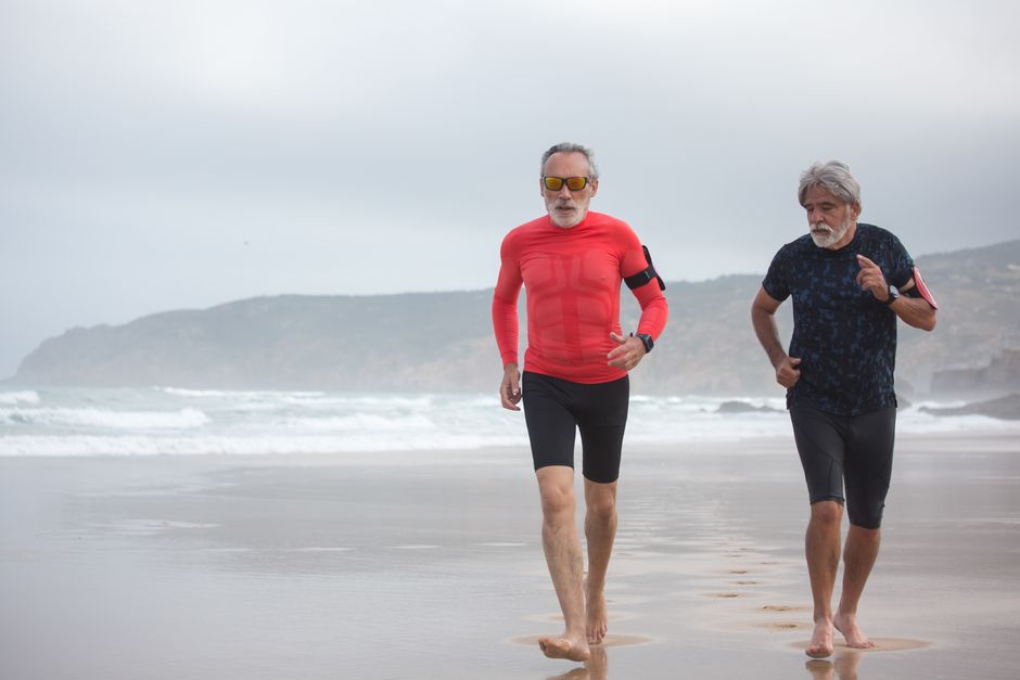 Two men over 50 jogging side by side on a beach, showing the kind of companionship and endurance that builds lasting loyalty.