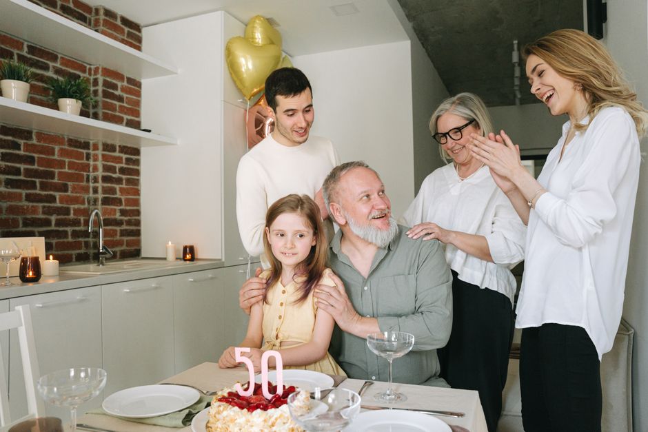 An older man surrounded by his loving family during a milestone birthday celebration, symbolizing lifelong loyalty and protection of loved ones.