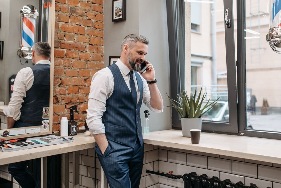 A man over 50 in business attire makes a phone call, perhaps to let someone know he's running late.