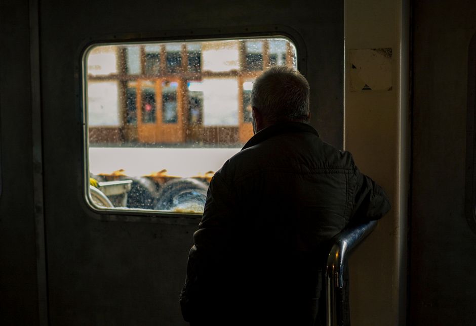 An older man stares silently out a window, reflecting on feelings of loneliness.