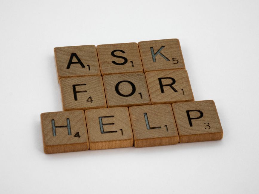 Wooden tiles spelling "Ask for Help," symbolizing the importance of reaching out when you're stuck.