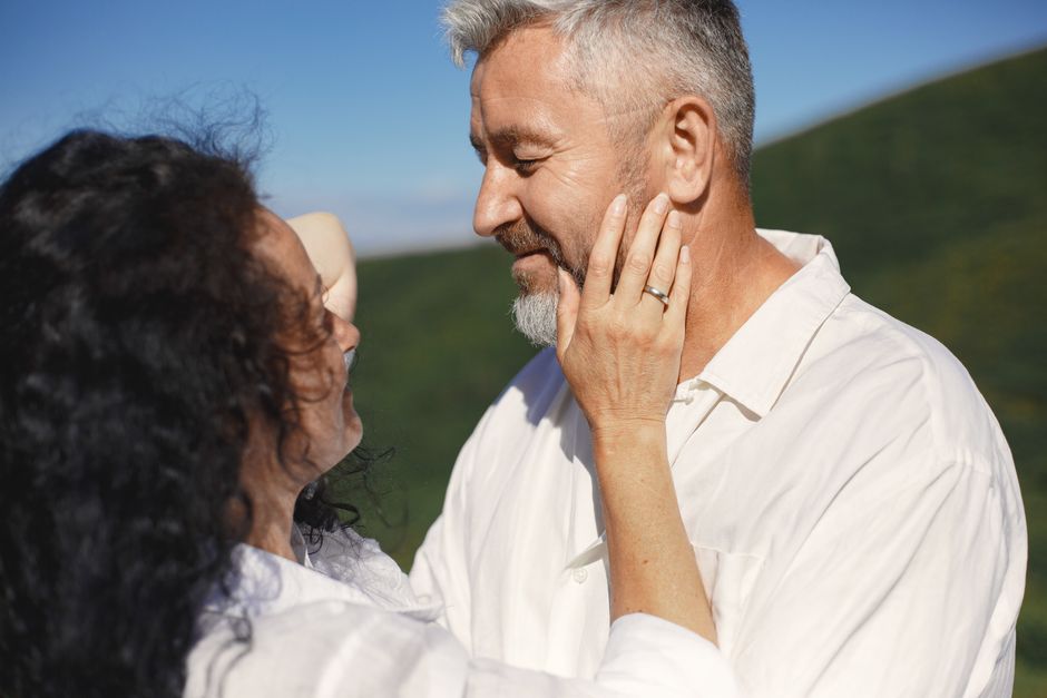 A woman over 50 tenderly touches her partner's face, showing a loving gesture that keeps men devoted for decades.