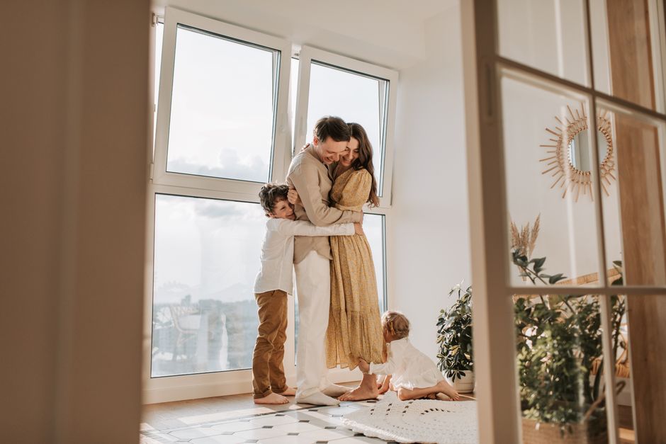 A couple shares an embrace while their children stay close by, highlighting the bond between partner and family.