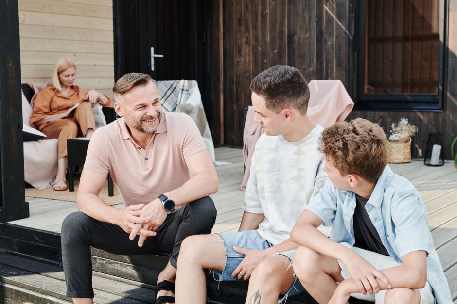 A father talks with his two adult sons outside, avoiding comparisons between them.