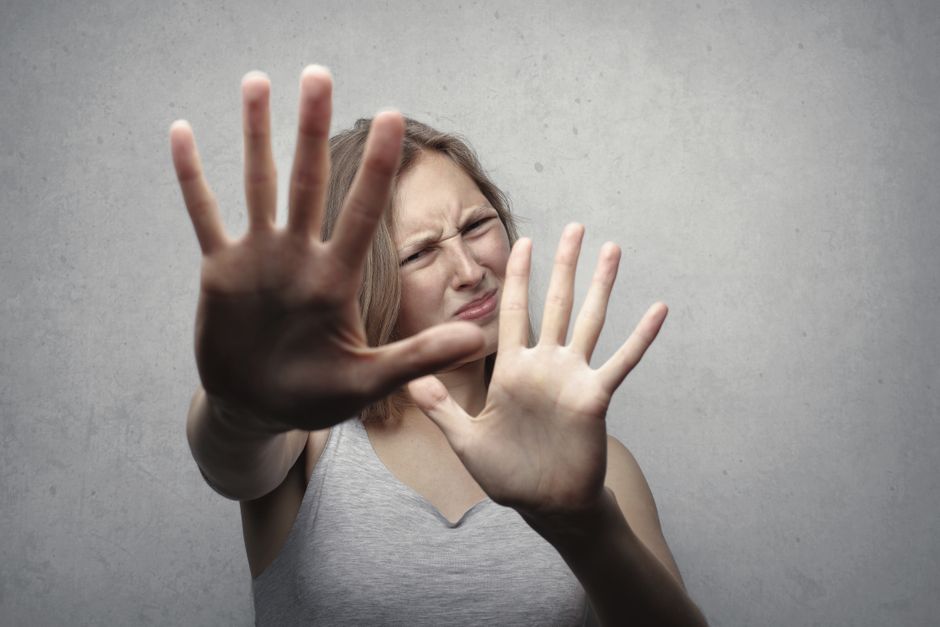 A woman raises her hands defensively, reflecting the fear and need to set boundaries when a partner makes threatening demands.