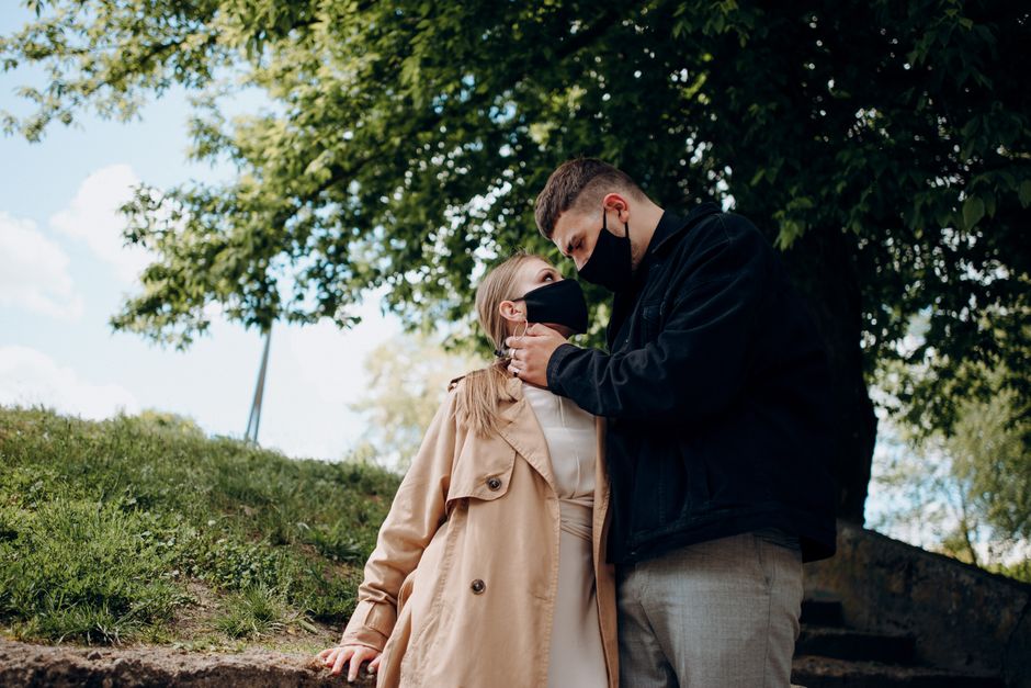 A couple embraces secretly outdoors, their faces partially hidden, symbolizing a relationship kept under wraps.