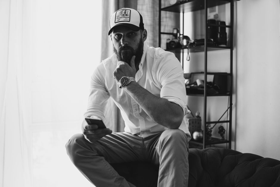 A man sits quietly in thought, hand resting on his chin, illustrating how male silence often reflects deep thinking rather than anger.