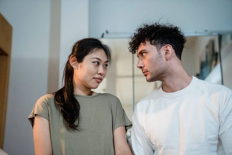 A couple exchanges a tense, searching look that hints at unspoken doubts about trust.