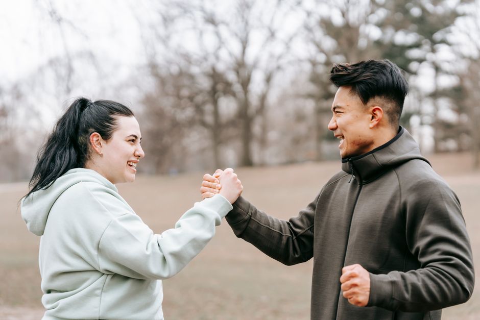 A supportive woman clasps hands with a man, encouraging him as he pushes through challenges, symbolizing a partner who believes he can do hard things.