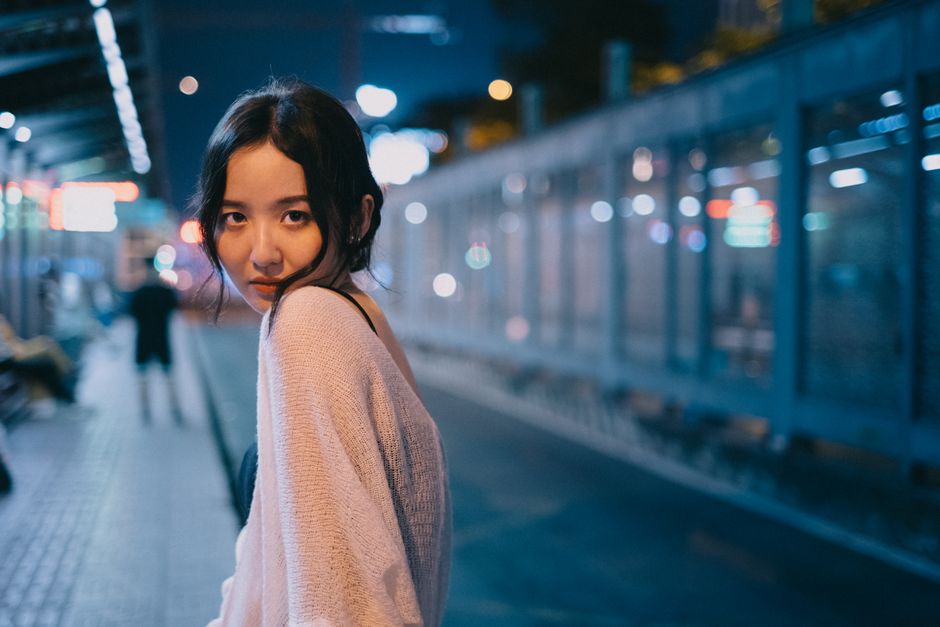 A woman glances back over her shoulder after walking past, catching your eye in the city night lights.