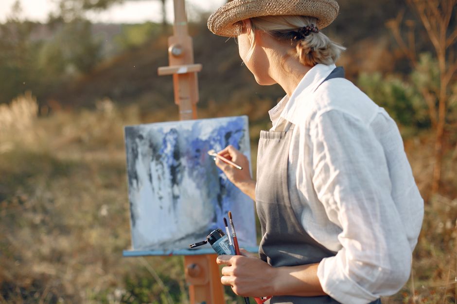 A woman enjoys her own personal hobby of painting outdoors, having something that belongs only to her.