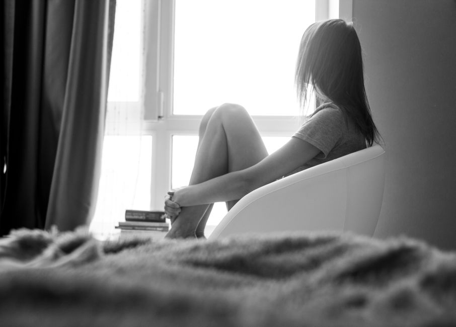 A woman sits alone by the window in quiet reflection, giving herself space to think.
