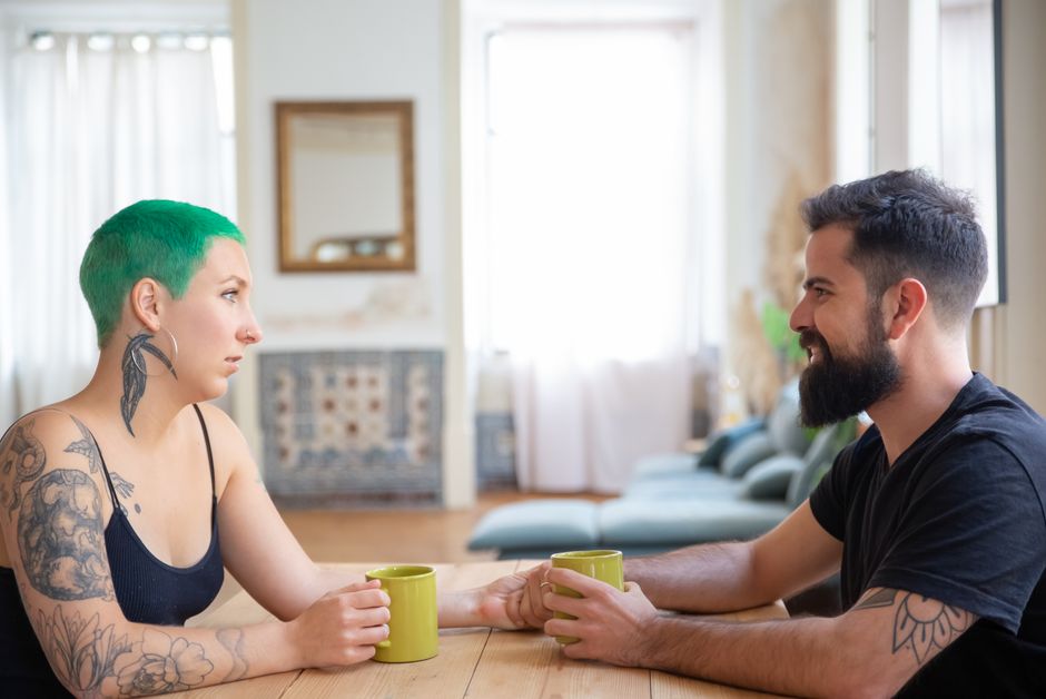 A man and woman sit across from each other with coffee mugs, deep in an engaging conversation, leaving room to talk more next time.