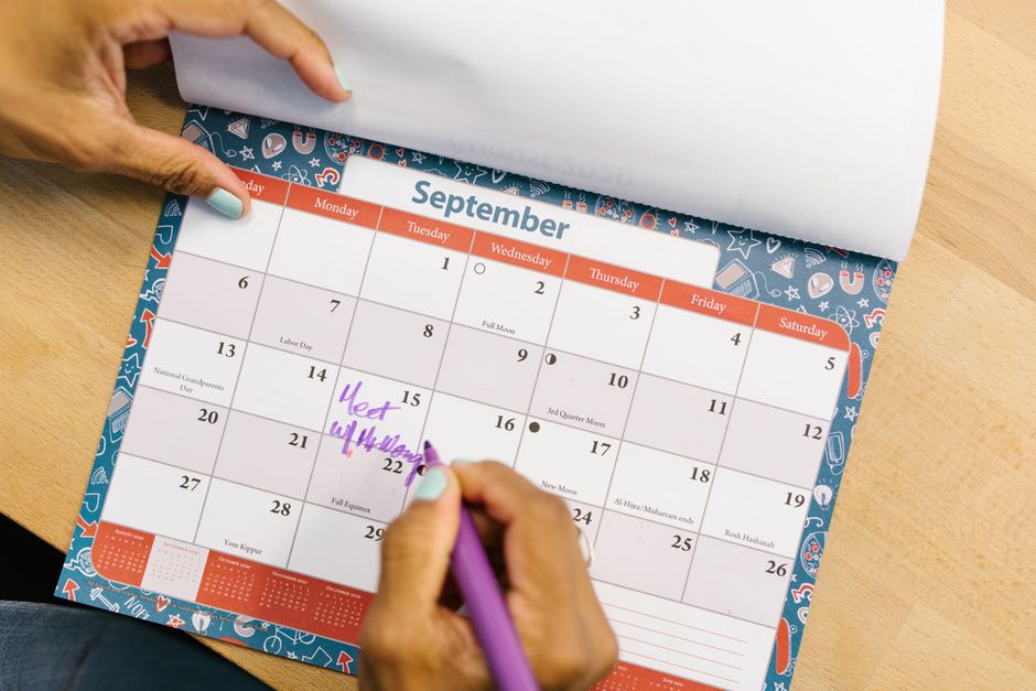 A woman writing her own plans on a calendar, keeping busy with her schedule instead of waiting around.
